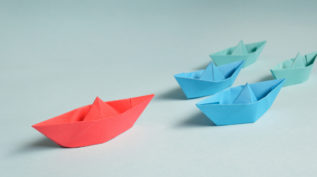 四个纸小船与一条红色的小船领导的方式